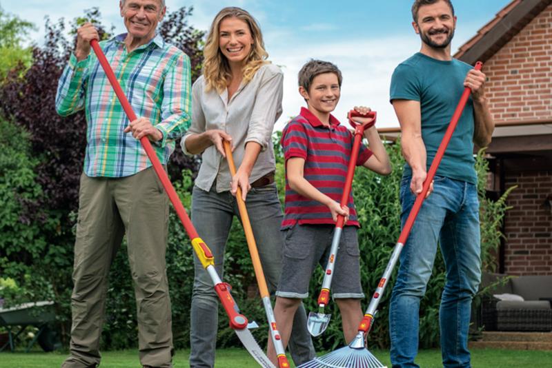 Family of four with gardening tools in a backyard